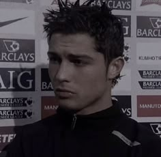 a man with spiked hair standing in front of a wall