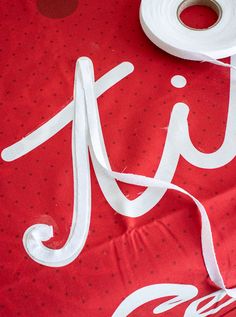 a roll of white tape sitting on top of a red table cloth with the word jit spelled out