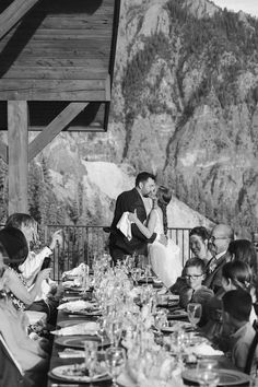 a bride and groom kissing at the end of their wedding reception in front of mountains