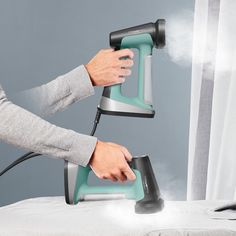 a person ironing fabric with an iron on top of the bed and steam coming out of it