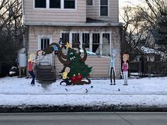 some people are standing in front of a house with a christmas tree on the side