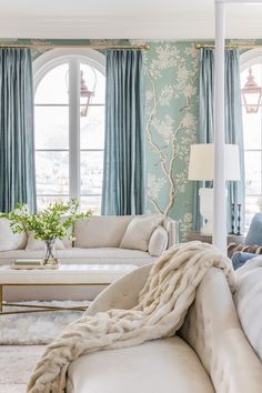 a living room filled with furniture and a large window covered in blue drapes