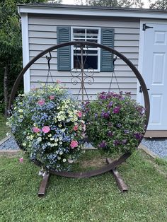 an outdoor garden with flowers in the center and a shed behind it, on grass