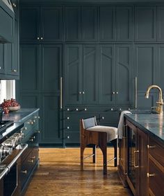 a kitchen with dark green cabinets and wooden floors