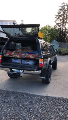 the back end of a black truck with its bed open and luggage in it's trunk