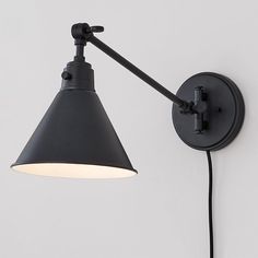 a black wall lamp with a white light on it's side and an arm that is attached to the wall