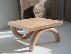 a wooden table sitting on top of a white floor next to a piece of wood