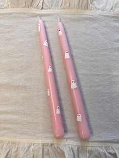 two pink candles with ghost decorations on them