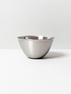 a silver bowl sitting on top of a white table