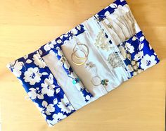 a blue and white flowered bag with jewelry on it sitting on a wooden table