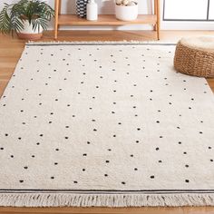 a white rug with black dots on it in front of a wooden shelf and potted plant