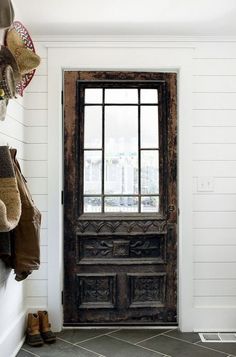 a wooden door sitting next to a white wall with shoes hanging on the side walk