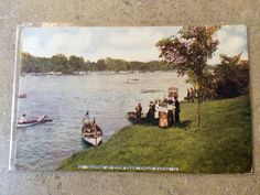 a group of people standing on top of a lush green field next to a lake