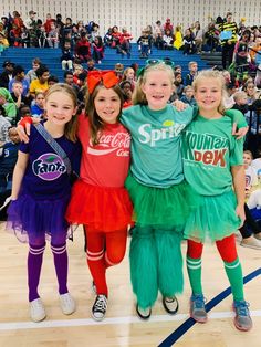 three girls in costumes standing on a basketball court