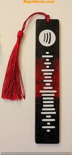 a bookmark with a red tassel hanging from it's side next to a flower