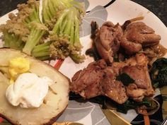 a plate topped with meat and vegetables on top of a table next to utensils