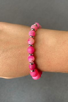 This is a pink beaded bracelet featuring a variety of round beads with different textures and shades of pink. The beads are separated by small silver spacer beads, adding a touch of contrast and elegance. The bracelet is elastic, allowing for a comfortable and adjustable fit on the wrist. The vibrant pink color and unique patterns make it a stylish accessory suitable for casual or dressy occasions. Pink Beaded Earrings, Pink Beaded Bracelet, Pink Beaded Bracelets, Pink Beads, Different Textures, Dress With Cardigan, Casual Denim, Faceted Bead, Stylish Accessories