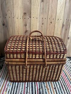 a large woven basket sitting on top of a striped table cloth next to a wooden wall