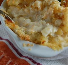 a bowl filled with macaroni and cheese on top of a table next to a fork