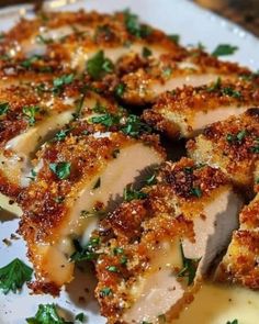 a white plate topped with sliced chicken covered in parmesan cheese and garnish