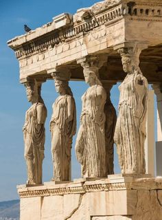 some statues on the side of a building with blue skies in the backround