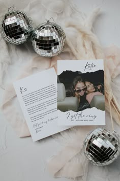 two disco balls and a card on top of a white table cloth with some paper