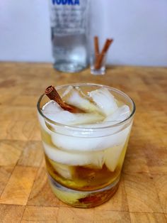 a glass filled with ice and cinnamon on top of a wooden table