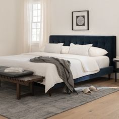 a bedroom with white walls and wood flooring has a large bed in the center