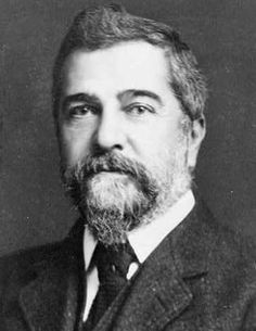 an old black and white photo of a man with a beard wearing a suit jacket