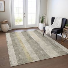 a living room area with a chair and rug on the hardwood floor next to a door