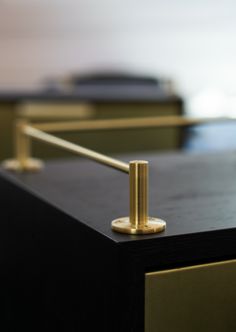 a close up of a black and gold table with a metal bar on the top