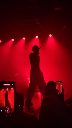 a man standing on top of a stage in front of microphones and red lights