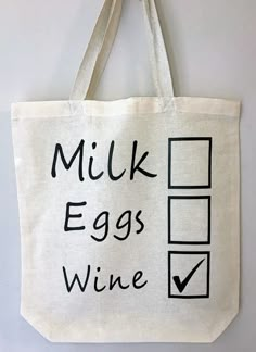 a tote bag with the words milk, eggs and wine on it hanging from a wall