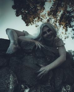 a woman laying on top of a rock next to a tree