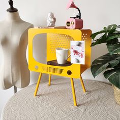 a yellow tv sitting on top of a table next to a potted plant