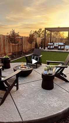 a patio with chairs and fire pit in the back yard at sunset or sunrise time