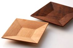 two wooden bowls sitting on top of a white table