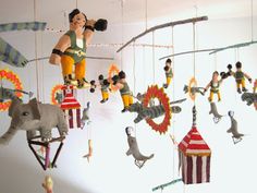 a mobile made to look like circus performers hanging from strings with elephants, giraffes and clowns on them