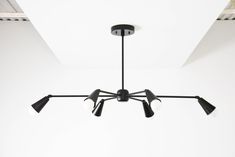 a black chandelier hanging from the ceiling in a room with white walls and beams