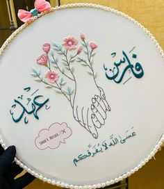 a person holding up a cake decorated with flowers and arabic writing in the shape of hands