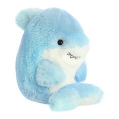 a blue and white stuffed animal sitting on top of a white floor next to a wall