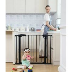 a woman standing next to a baby in a kitchen