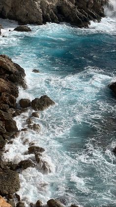 an ocean view with waves crashing on the rocks