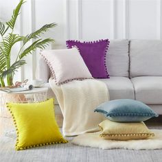 pillows on the floor in front of a couch and table with a potted plant