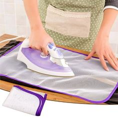 a woman ironing fabric on top of an ironing board with a purple and white cover