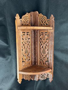 a wooden shelf with carved carvings on the front and back sides, sitting against a black background