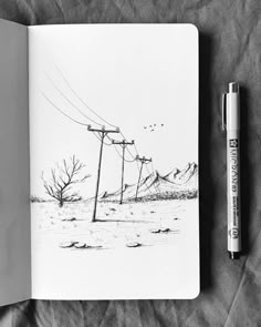 a pen is sitting on top of a notebook with an ink drawing of power lines