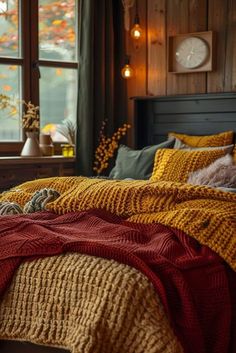 a bed with yellow and red blankets on top of it in front of a window