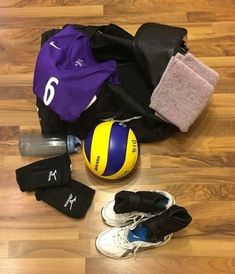 a volleyball ball, gloves and other sports equipment are on the floor next to each other