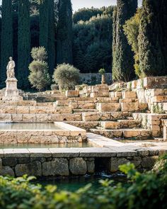 an outdoor fountain surrounded by stone steps and trees